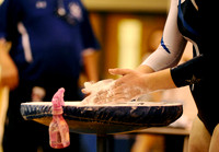A West Potomac student puts chalk on her hands before her turn on the uneven bars during a meet at West Potomac High School on January 3, 2011.