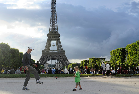A father and son play with a ball before the Bastille Day fireworks show on the Champ de Mars in Paris, France.July 14, 2012